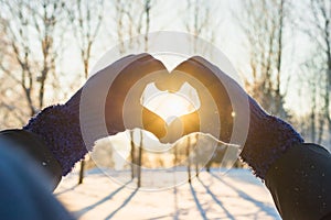 Woman making heart symbol with hands.sunny winter evening, sunrays, Valentines day, Love concept