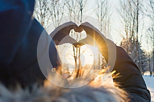 Woman making heart symbol with hands.sunny winter evening, sunrays, Valentines day, Love concept