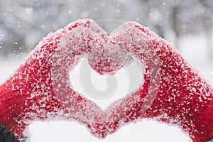 Woman making heart symbol with snowy hands