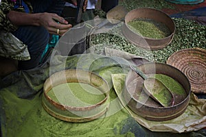 Woman making henna powder from dried henna leaves in a traditional way