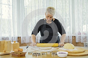 Woman making homemade cookies rolls dough with rolling pin for homemade baking