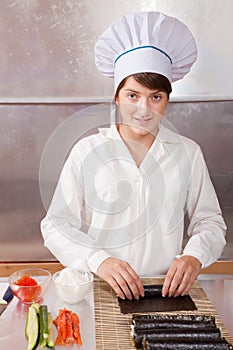 Woman making japanese sushi rolls