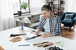 woman making or knotting macrame on table at home