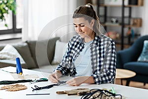 woman making or knotting macrame on table at home
