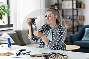 woman making or knotting macrame on table at home
