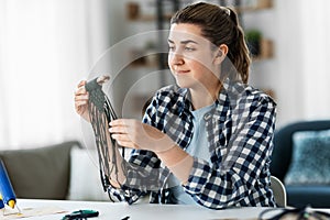 woman making or knotting macrame on table at home