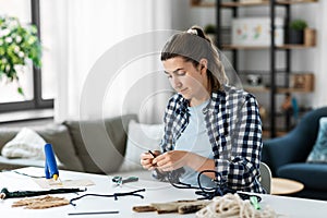 woman making or knotting macrame on table at home