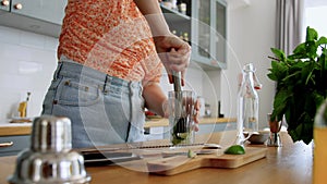 woman making mojito cocktail drink at home kitchen