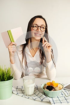 Woman making notes in notepad with healthy food on table