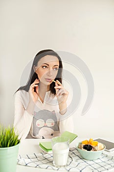 Woman making notes in notepad with healthy food on table