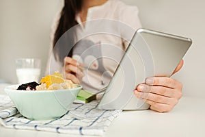 Woman making notes with tablet and healthy food on table