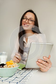 Woman making notes with tablet and healthy food on table