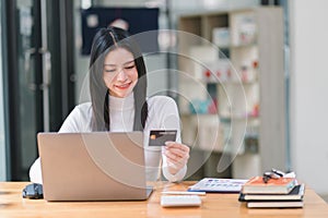 A woman making an online purchase on a computer using a mockup credit card.