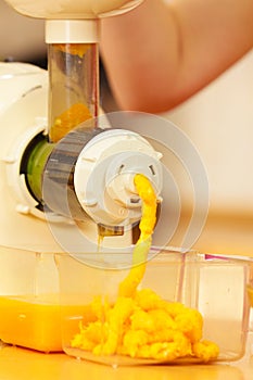 Woman making orange juice in juicer machine