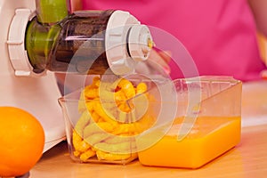 Woman making orange juice in juicer machine