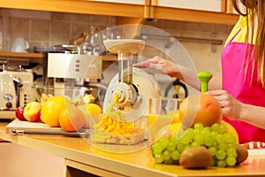 Woman making orange juice in juicer machine