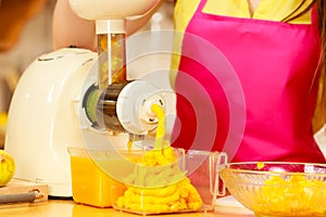 Woman making orange juice in juicer machine