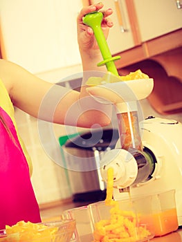 Woman making orange juice in juicer machine