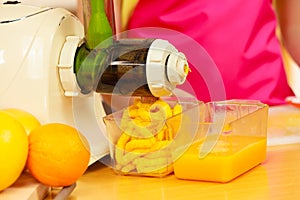 Woman making orange juice in juicer machine