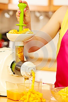 Woman making orange juice in juicer machine