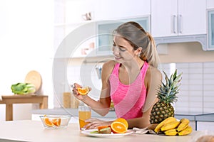 Woman making orange juice at table in kitchen