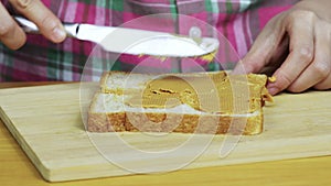 Woman making a peanut butter and Strawberry Jam sandwich