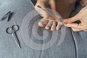 Woman is making pedicure herself removing cuticle and pterygium on toe, closeup. photo