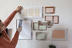 Woman making photo of white wall with set of different empty vertical and horizontal picture frames