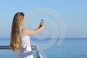 Woman making a photograph of the sea with a smart phone