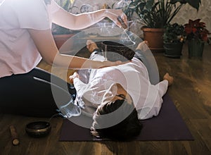 Woman making relaxing massage for young man.  Meditation, sound therapy with Tibetan singing bowls