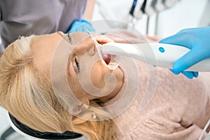 Woman making scan of jaw in dental cabinet