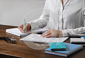 Woman making schedule using calendar at table, closeup