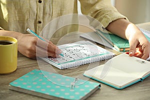 Woman making schedule using calendar at table, closeup