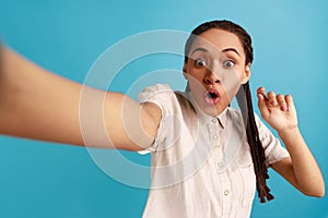 Woman making selfie, looking at camera with big eyes and open mouth, point of view photo.