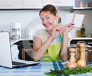 Woman making shopping list at kitchen