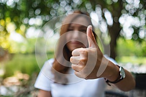 A woman making and showing thumbs up hand sign