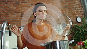 Woman making soup in kitchen. Girl adding salt to boiling pot.