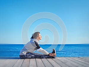 Woman making sport on a wooden pier. Sea and sky background. t.