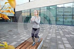 Woman making step exercise on city street bench