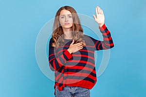 Woman making swearing gesture and holding arm on chest, taking oath, pledging allegiance.