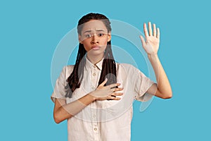 Woman making swearing gesture and holding arm on chest, taking oath, pledging allegiance.