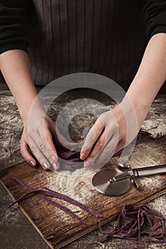 Woman making tagliatelle nest on kitchen table