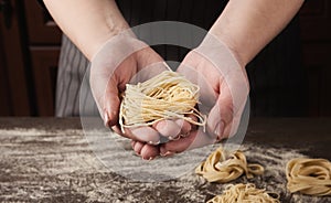 Woman making tagliatelle nest on kitchen table