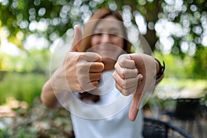 A woman making thumbs up and thumbs down hands sign