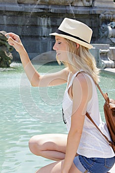 woman making wish as she drops coin into fountain