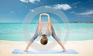 Woman making yoga forward bend on beach