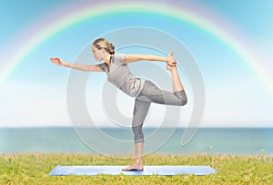 Woman making yoga in lord of the dance pose on mat