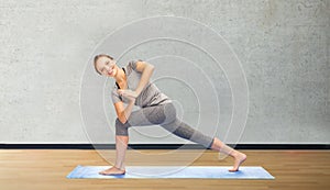 Woman making yoga low angle lunge pose on mat
