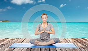 Woman making yoga meditation in lotus pose on mat