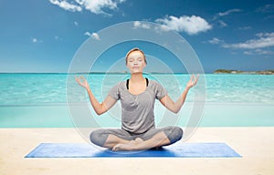 Woman making yoga meditation in lotus pose on mat